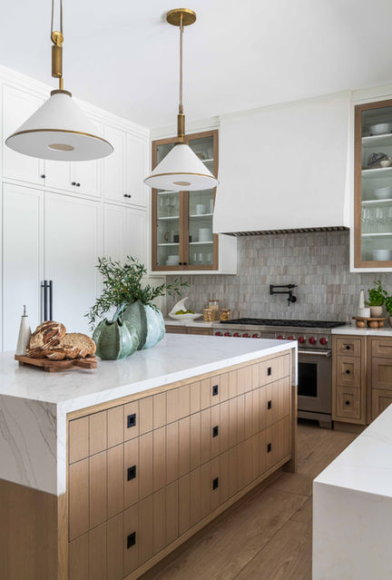 Kitchen island with marble countertop, warm wood cabinetry, pendant lighting, glass-front cabinets, and subtle tile backsplash.