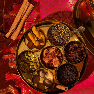 Traditional brass spice box with various whole spices