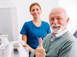 A senior man gives a thumbup at the dentists office
