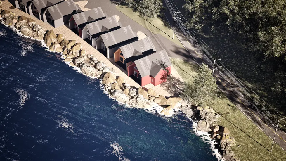 Aerial view of modern seaside cabins built beside rocky coastline and deep blue water.