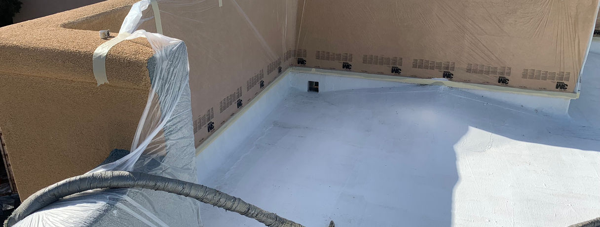 A flat roof with surrounding walls taped off for spray foam application.