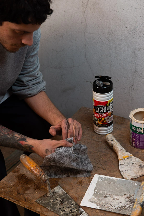 Worker using a Hyper Wipes wipe to clean dirty hands at a workshop bench