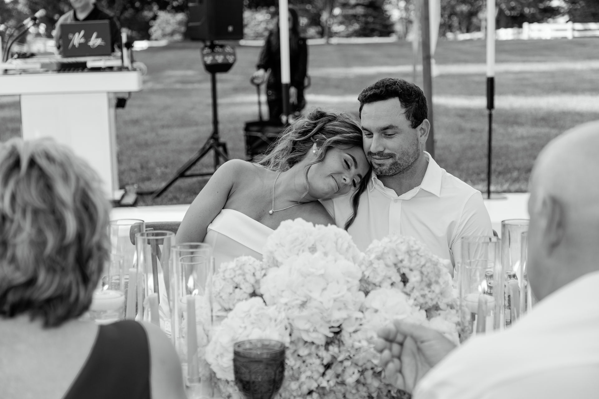 Bride and groom listen to toast given by family during their backyard wedding reception