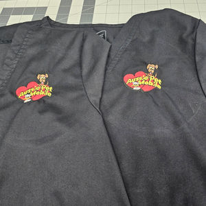 Two black scrubs embroidered with adorable dog logos