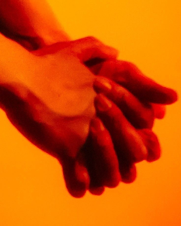 Deux mains qui se frôlent dans une lumière orangée