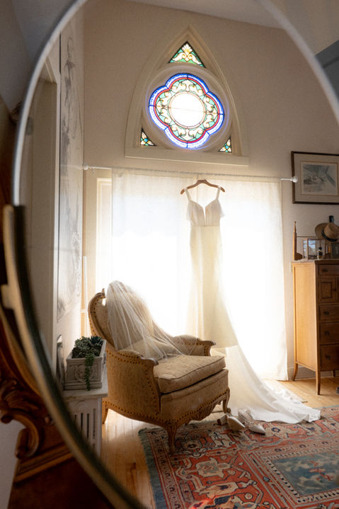 Gown under the stained glass window in the Bridal Suite at Penobscot Bay Estate, a Maine Waterfront Venue, photo by Hannah Jenkins Photography