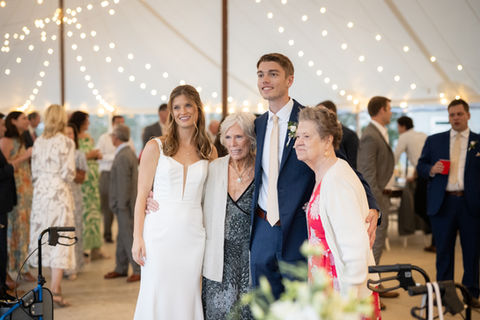 Couple poses with family under Sailcloth Tent at Penobscot Bay Estate, Tented Waterfront Wedding Venue, Photo by Hannah Jenkins Photography