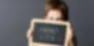 displeased preschool child hiding himself behind a school slate with 'poux' written in Fre