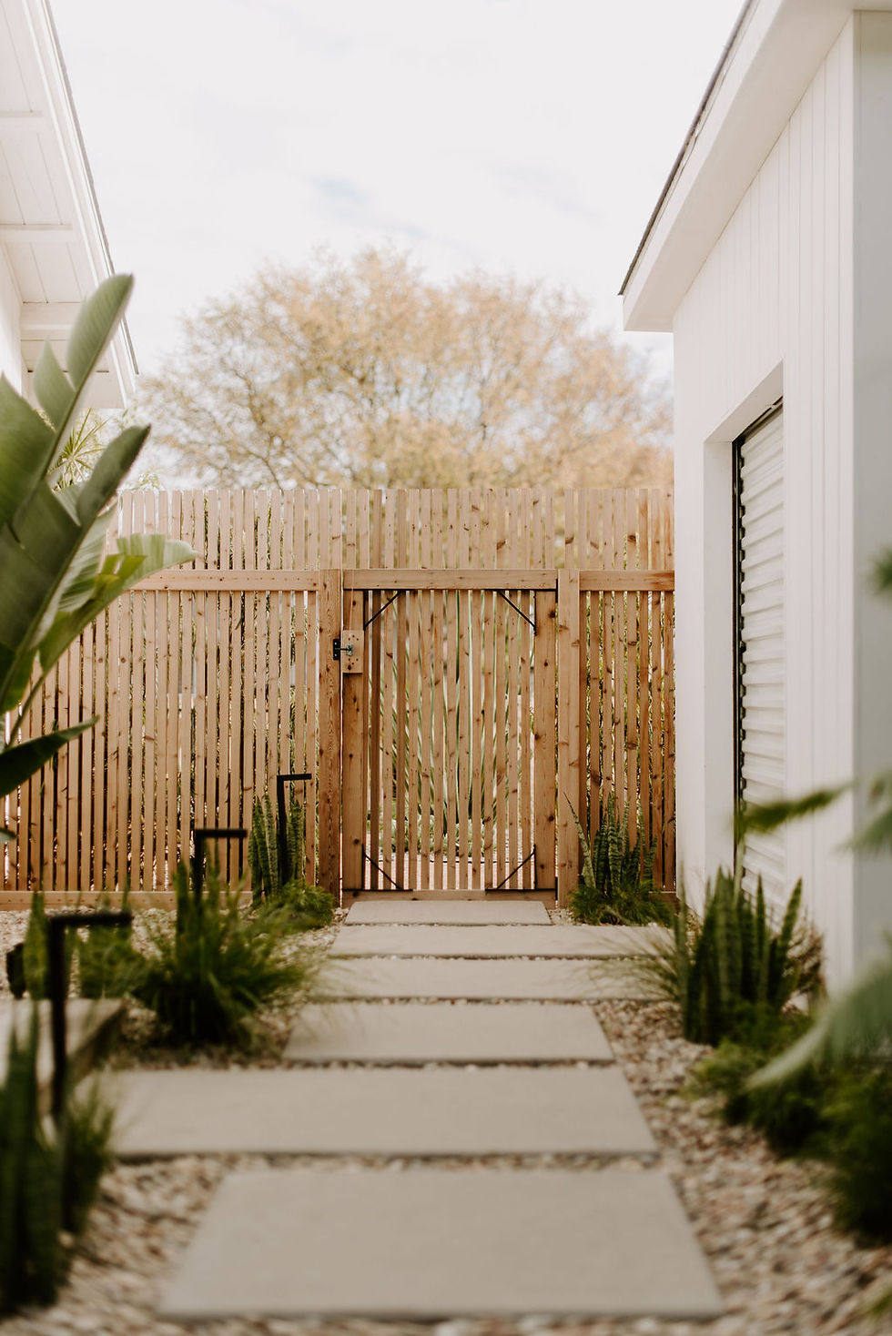Concrete steppers in a side yard walkway leading to a modern vertical cedar fence.