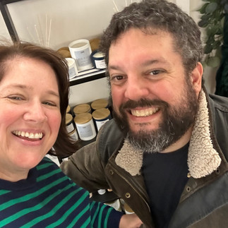 Elizabeth, founder of Thimble and Hearth, and her husband posing in front of candle display