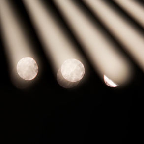 Lichtreflexion auf einer schwarzer Karosserie, die an einem Auto zu sehen ist. In dunklem Hintergrund, künstlerische Darstellung.