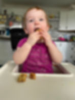 A 1-year-old takes a big bite of carrot breakfast cake.