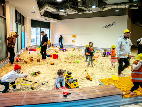 Children playing in a large indoor sand pit at a party.