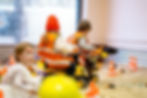Children in safety vests playing with toy tractors