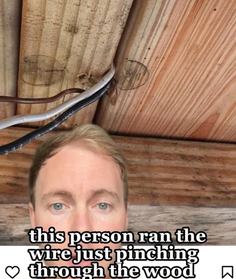 Man's face below wooden ceiling with wires improperly installed through holes. Text on image: this person ran the wire just pinching through the wood.