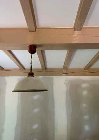 Plafond en poutres de bois avec luminaire suspendu.