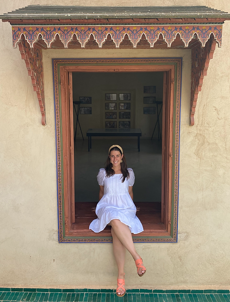Photo of Rachel Benaim-Abudarham, the founder, sitting by a decorative window. 
