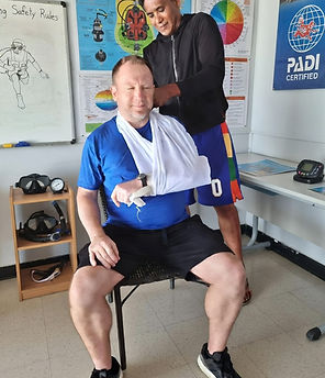 Emergency First Response training demonstrating proper sling application during first aid and rescue practice at Maharlika Dive Center.