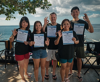 Students proudly holding PADI Open Water certificates after training in Anilao
