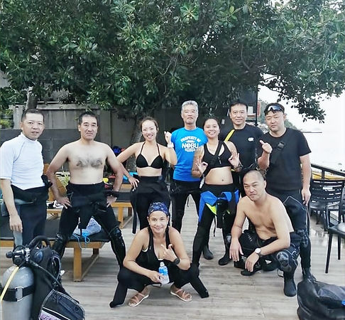 Group of scuba divers posing after a fun dive at a beach resort in Anilao, Batangas, wearing wetsuits and dive gear with tropical seaside views at Maharlika Dive Center