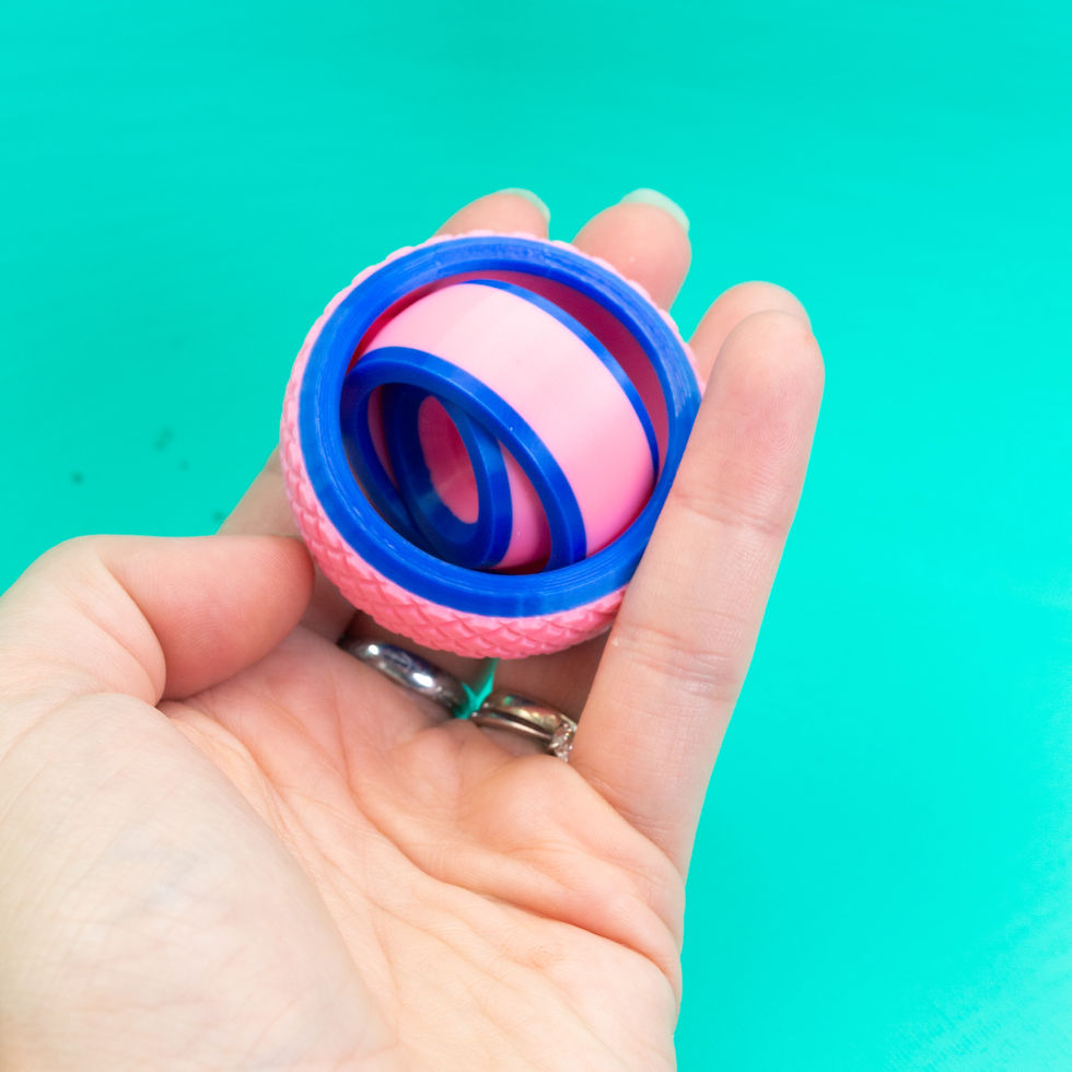 Thumbnail: Hand holding a pink and blue gyroscope fidget toy.