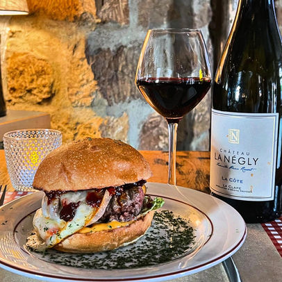 Burger servi sur assiette avec un verre de vin rouge et une bouteille de vin