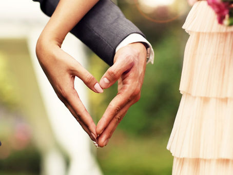 A couple side by side, hands in the shape of a heart