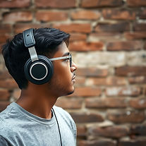 a photograph of a young man wearing headphones looking at an old brick wall.jpg