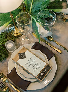 Sophisticated table setting with lush greenery and ferns, featuring a customized paper menu and white candles
