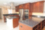 Kitchen remodel in Crown Hill, Seattle as part of a whole house renovation and accessory dwelling unit project, featuring custom wood cabinetry, large island with cooktop, granite countertops, and stainless steel appliances.