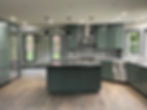 Custom kitchen remodel in Snohomish, Washington featuring modern green cabinetry, large island with stone countertops, geometric tile backsplash, stainless steel appliances, and open-concept layout as part of a whole house renovation.