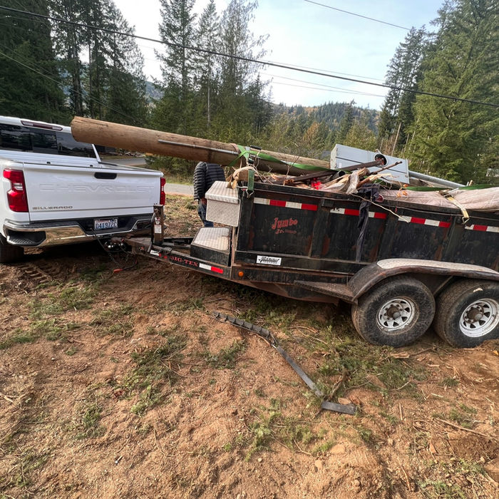 Heavy-duty junk removal truck hauling a large utility pole and debris in Whatcom County.