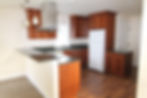 ADU kitchen remodel in Crown Hill, Seattle featuring custom wood cabinets, dark countertops, compact open layout, and modern lighting designed for efficient small space living.