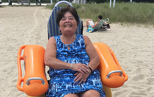 Happy woman in a floating wheelchair on the beach