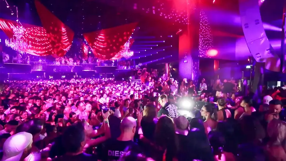 Packed crowd under pink lights and lasers inside Hi Ibiza