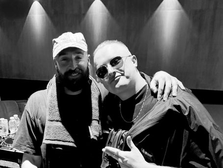 NOTION & MNEEMO (Yaroslav Gorovoy) in black outfits, one with a towel around his neck and the other wearing sunglasses, pose happily under warm lighting indoors during Mixmag Cover Moment.