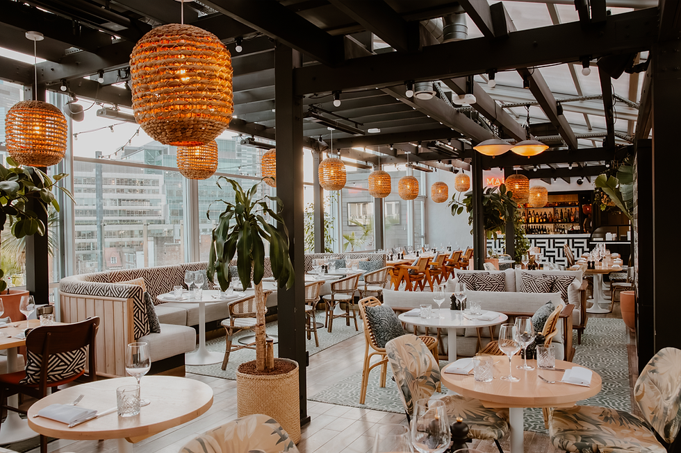 45 London on 45 Curtain Road. Chic restaurant interior with woven pendant lights, patterned cushions, and plants. Wooden tables set for dining, surrounded by floor-to-ceiling windows.