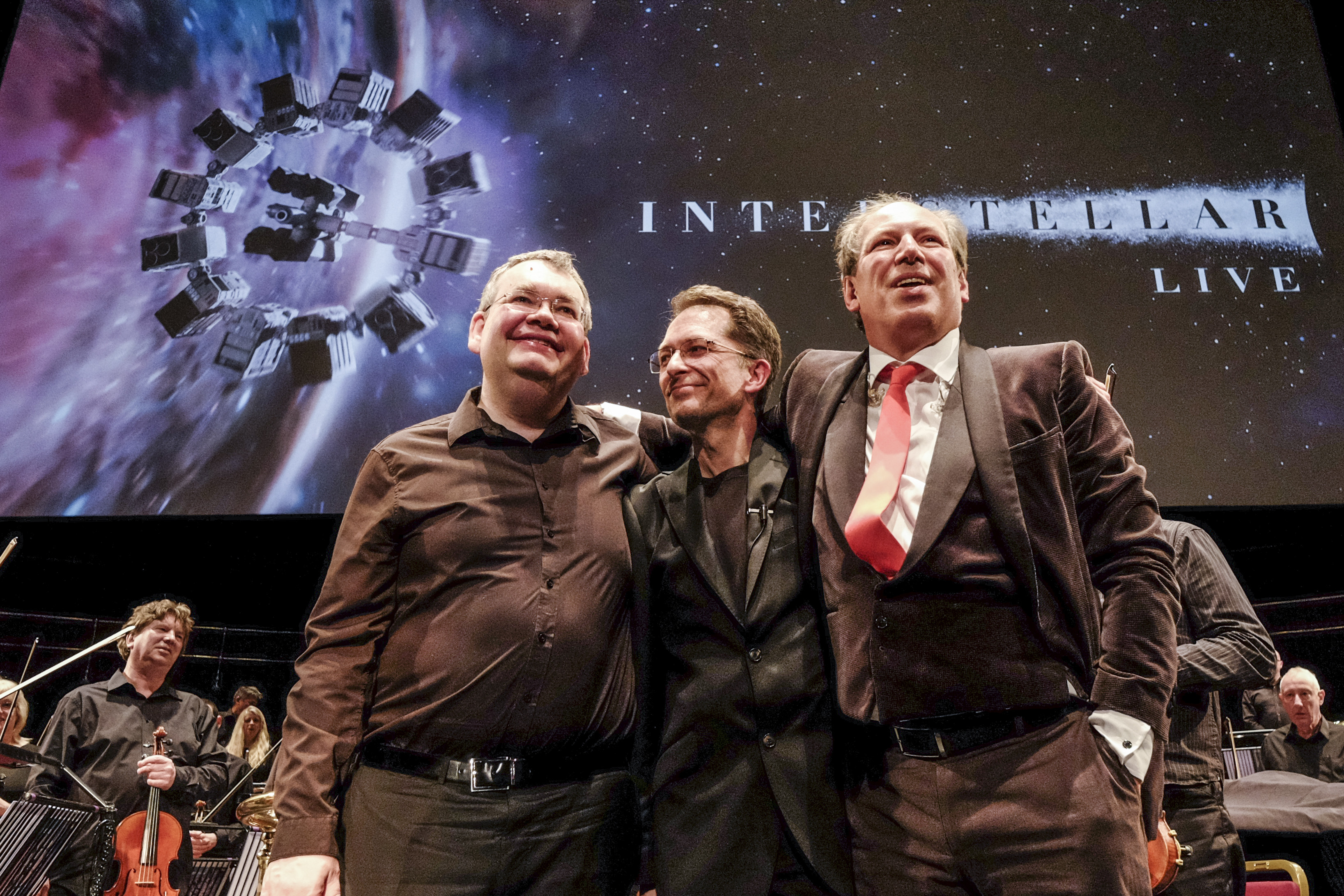 Hans Zimmer, Gavin Greenaway and Roger Sayer together on stage beneath the Interstellar Live screen