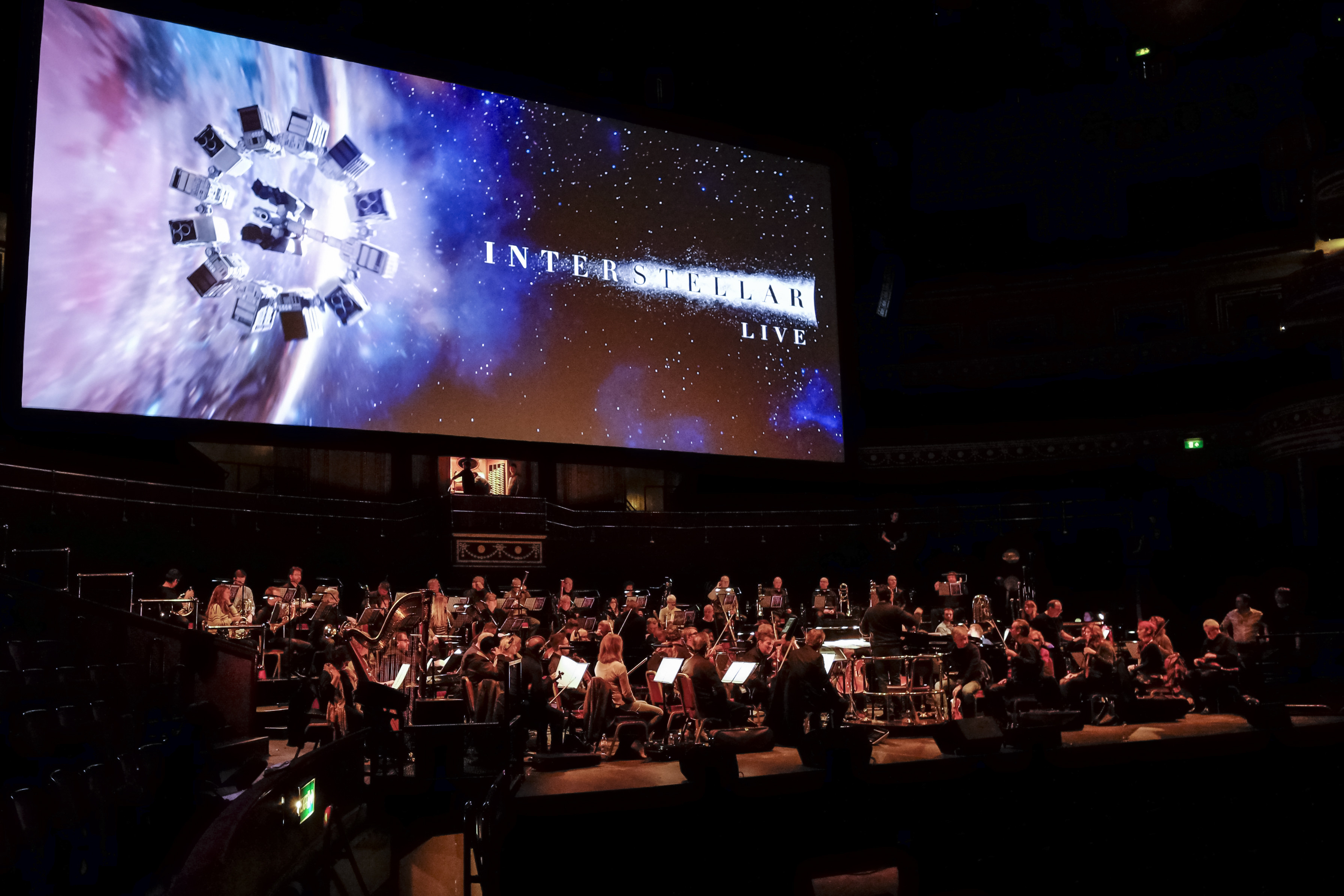 Musicians rehearsing on stage beneath the large Interstellar Live projection at the Royal Albert Hall