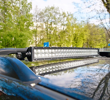 Closeup of an LED light bar installed on the roof of an off-road vehicle, reflecting trees