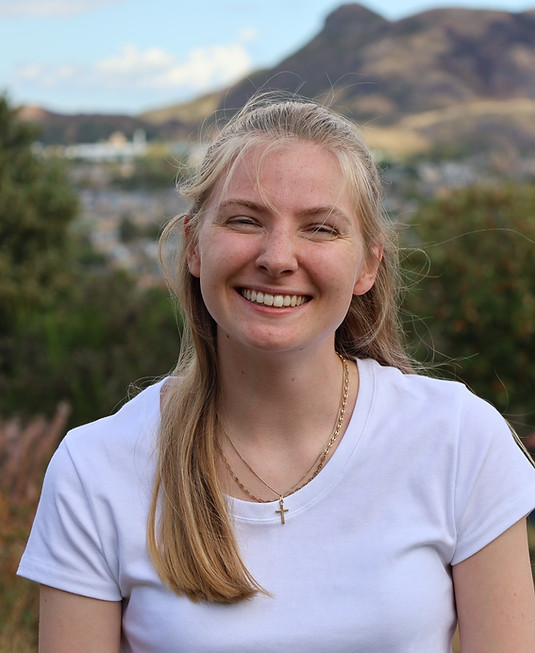 Woman smiling at camera in front of Arthurs Seat