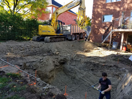 Excavator digging backyard pool site near home with buried utility infrastructure risks