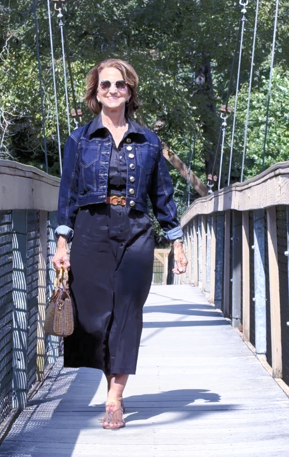 petite woman over 60 wearing a a black midi dress with a crop denim jacket
