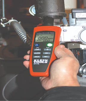 Person holding a carbon monoxide meter with 0.00 ppm readings, Klein Tools.