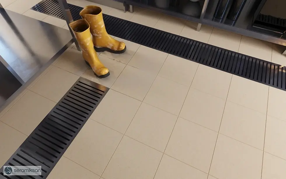 Bottes jaunes sur un sol carrelé avec des grilles de drainage.