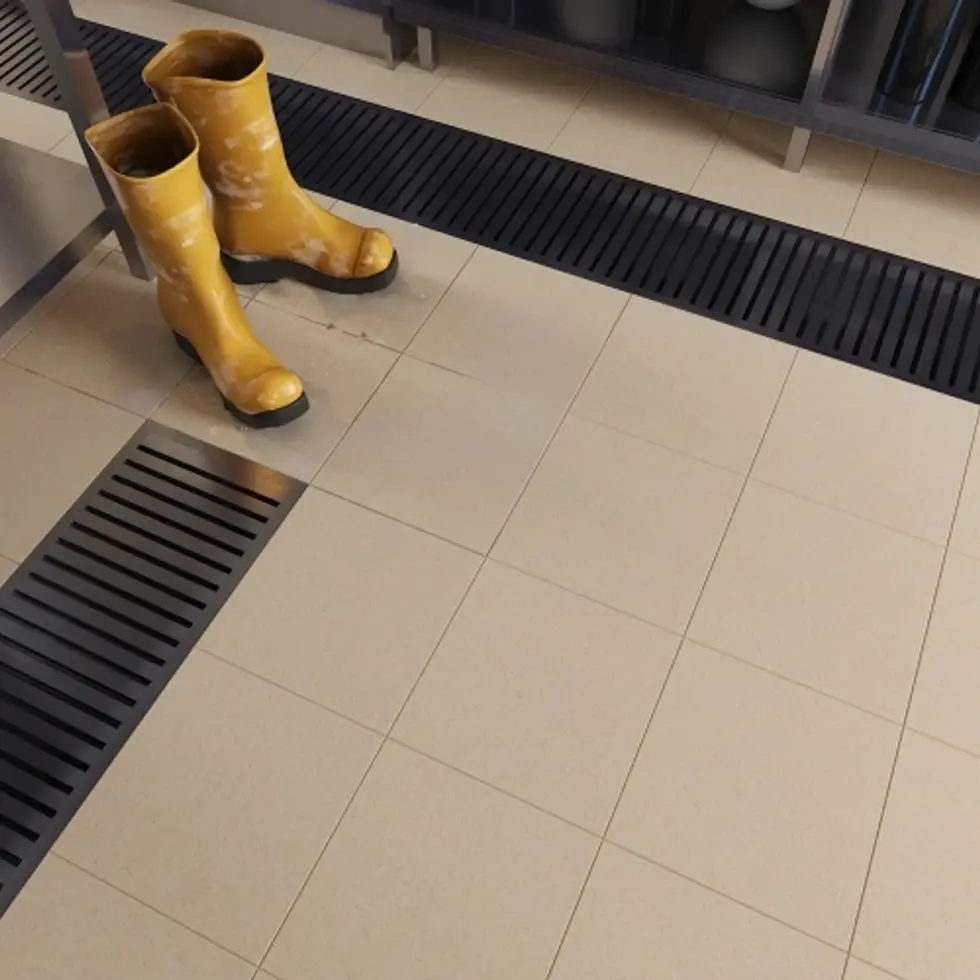 Bottes jaunes sur un sol carrelé avec des grilles de drainage.