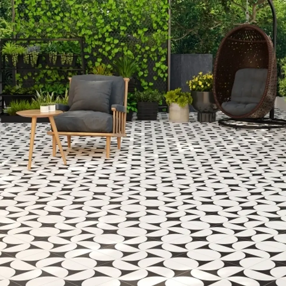 Terrasse carrelée avec motifs noirs et blancs, chaises et plantes.