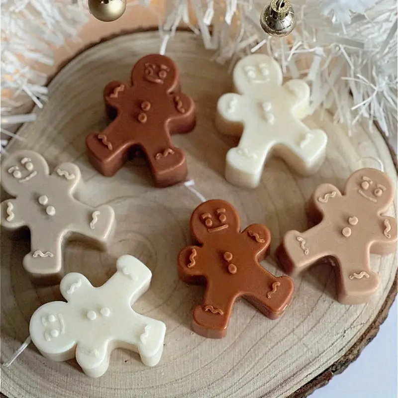 Assorted gingerbread-shaped wax melts in brown and cream tones arranged on a wooden surface