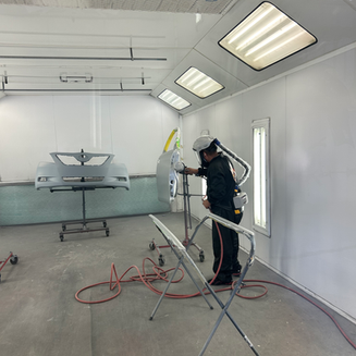Technician painting door in painting booth