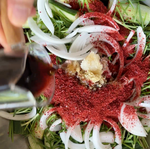 seasoning ingredients, including gochugaru, garlic, and fish sauce, added on top of sliced onions and chives.